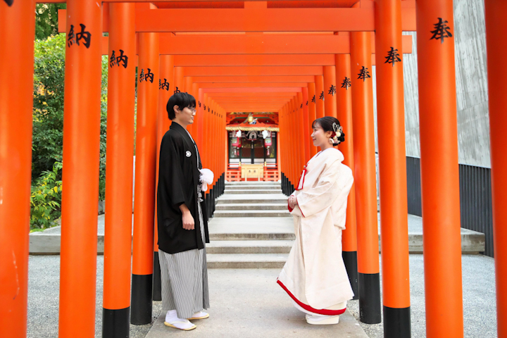 生田神社にて立ち並ぶ鳥居の中で見つめあう新郎新婦