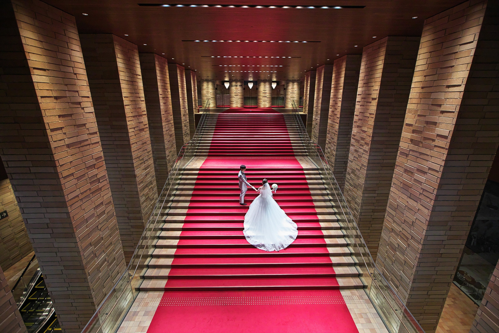 結婚式持ち込みカメラマンが撮影：フェスティバルホールの大階段で新婦の手を引く新郎